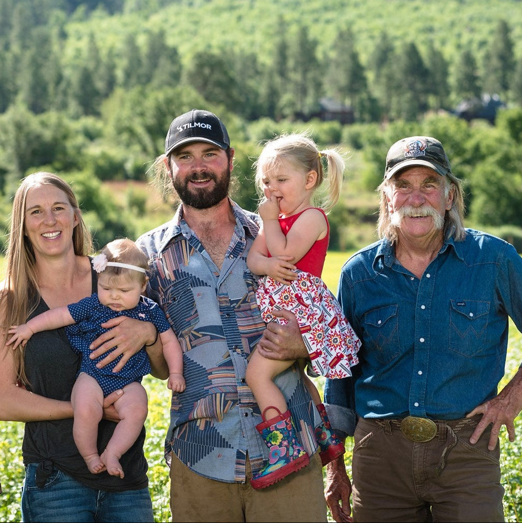 Family of five standing in a field with mountains in the background